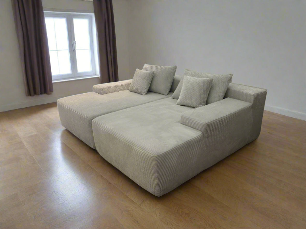 image Beige sectional sofa in a room with wooden flooring and a window.